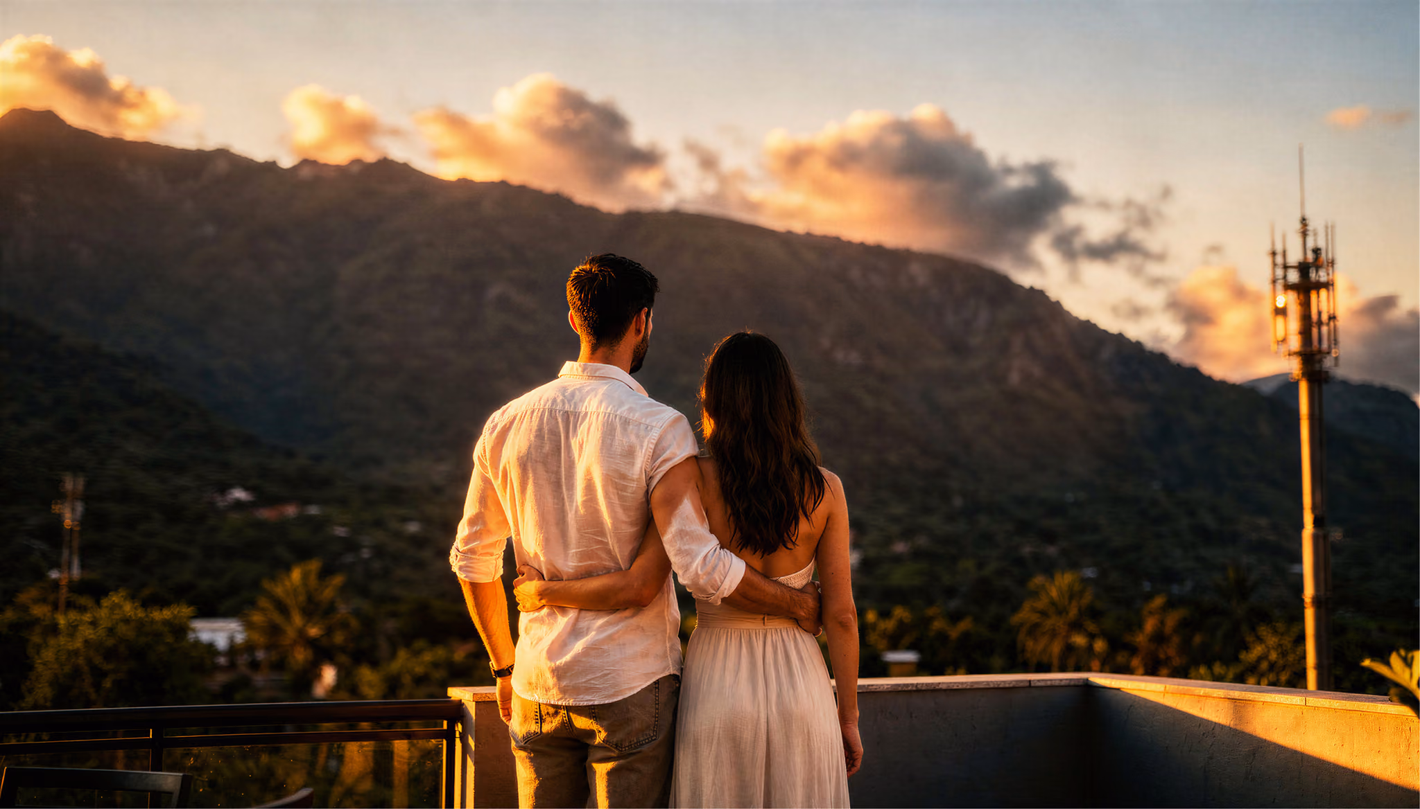 Casal admirando as montanhas ao pôr do sol a partir da cobertura